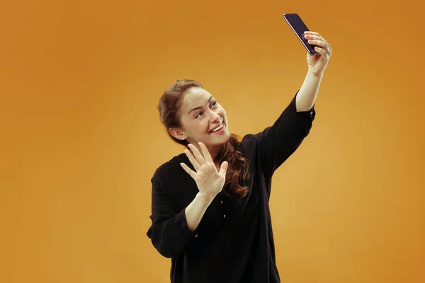 Portrét usmívající se příležitostné šťast zobrazuje prázdná obrazovka mobilní telefon izolované zlaté pozadí — Stock fotografie