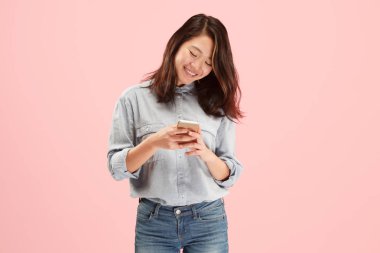 Pembe arka planda cep telefonu stüdyosu kullanan güzel bir kadın.