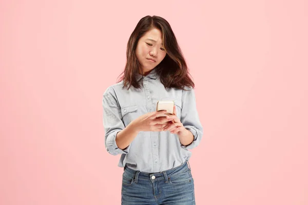 Jeune belle femme utilisant studio de téléphonie mobile sur fond de couleur rose — Photo