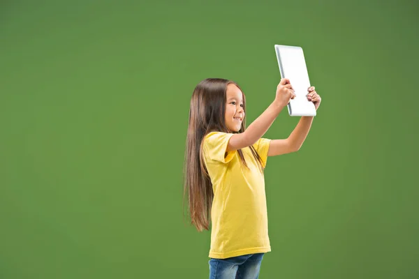 Chica adolescente con portátil. Me encanta el concepto de computadora. Atractivo retrato frontal femenino de media longitud, fondo de estudio verde de moda . — Foto de Stock