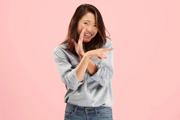 Die junge Frau flüstert ein Geheimnis hinter ihrer Hand über rosa Hintergrund — Stockfoto