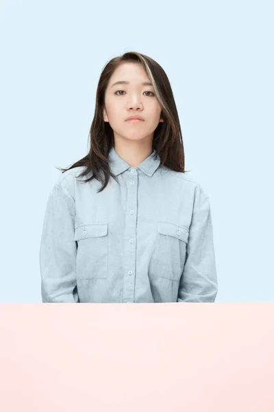 The serious business woman sitting and looking at camera against blue background. — Stock Photo, Image