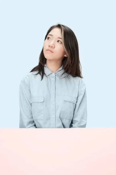 The serious business woman sitting and looking up against blue background. — Stock Photo, Image
