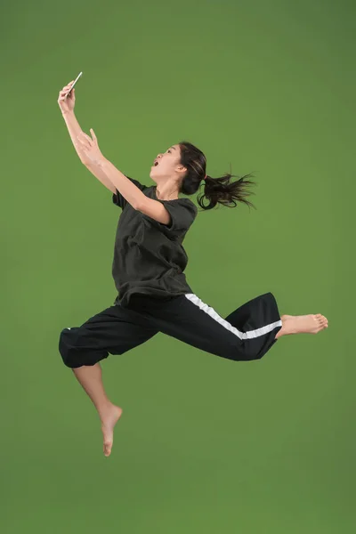 Свобода в русі. Красива молода жінка стрибає на зеленому тлі — стокове фото