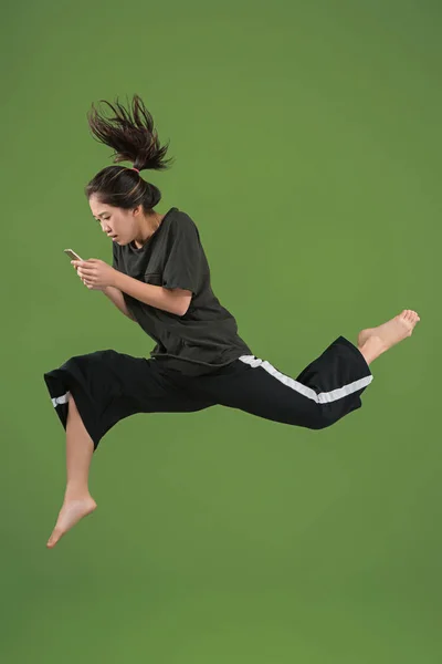 Liberdade em movimento. Mulher muito jovem pulando contra fundo verde — Fotografia de Stock