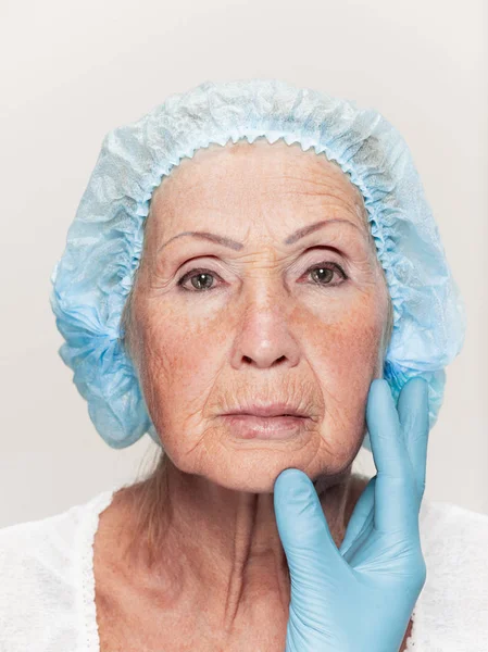 Ahli bedah melakukan pemeriksaan kulit pada usia pertengahan wanita sebelum operasi plastik — Stok Foto