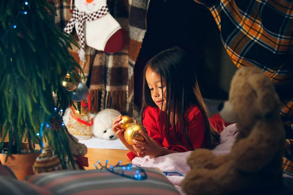 Noël, vacances et concept d'enfance - fille heureuse en vêtements rouges décorant sapin naturel — Photo