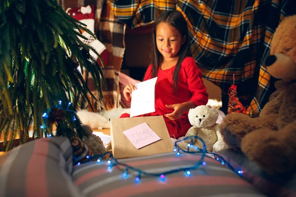 Feliz Natal e Boas Festas. Menina bonito escreve a carta para Papai Noel perto da árvore de Natal — Fotografia de Stock