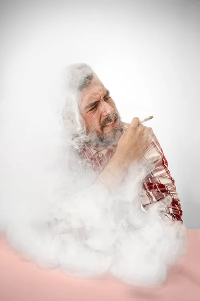 Красивий хіпстер палить сигарету вдома. Людина дивиться вгору і насолоджується вільним часом . — стокове фото