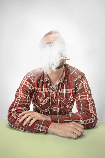 Hombre hipster guapo fumando cigarrillo en casa. Hombre mirando hacia arriba y disfrutando de pasar tiempo libre . — Foto de Stock