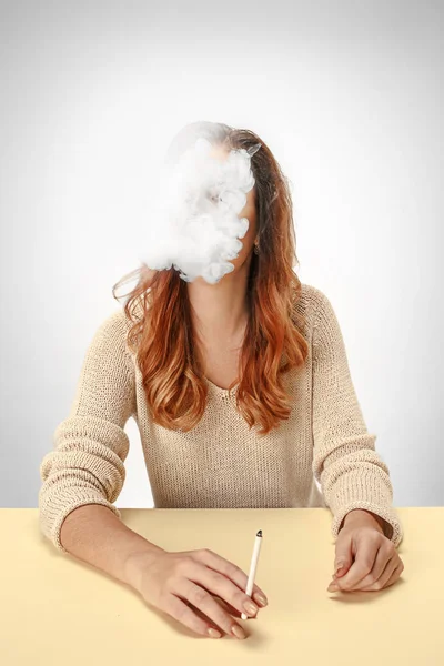 Mulher tranquilo sentado e fumando descansando na mesa. Nuvem de fumo a cobrir-lhe o rosto. Espaço de cópia — Fotografia de Stock
