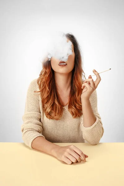 Mujer tranquila sentada y fumando descansando en la mesa. Nube de humo cubriendo su cara. Copiar espacio — Foto de Stock