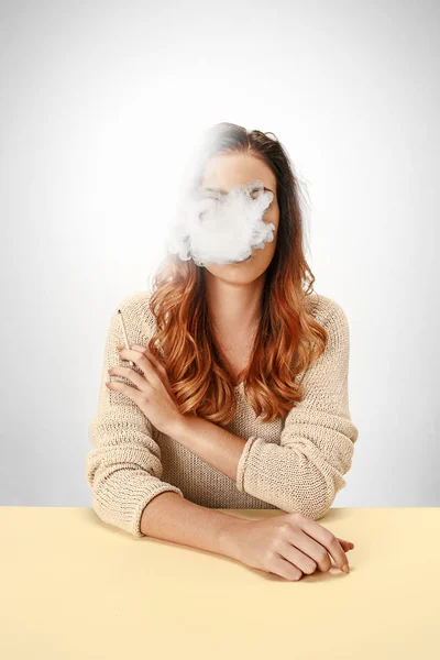 Mulher tranquilo sentado e fumando descansando na mesa. Nuvem de fumo a cobrir-lhe o rosto. Espaço de cópia — Fotografia de Stock