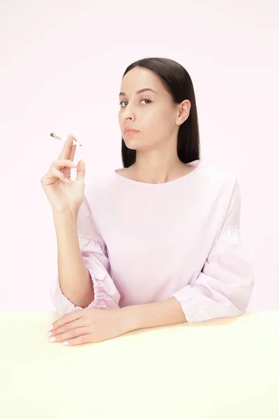 Guapas mujeres jóvenes fumando mientras están sentadas en la mesa del estudio. Colores de moda — Foto de Stock
