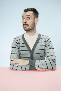 Mavi bir arka plan üzerinde bir masada oturan sürpriz iş adamı