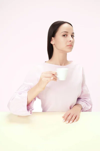 Bela mulher solitária sentada no estúdio e olhando triste segurando a xícara de café na mão. Closeup tonificado retrato — Fotografia de Stock