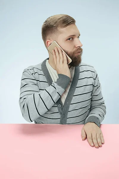 Verbaasd zakenman praten over telefoon zitten aan de tafel — Stockfoto