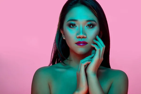 High Fashion model woman in colorful bright lights posing in studio