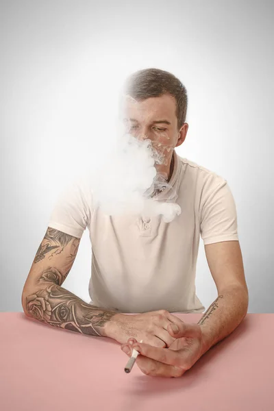 Hombre hipster guapo fumando cigarrillo en casa. Hombre mirando hacia arriba y disfrutando de pasar tiempo libre . —  Fotos de Stock