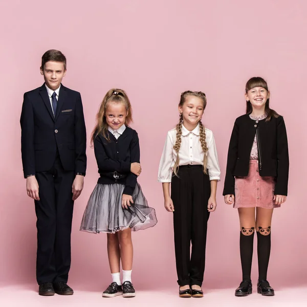 Милі стильні діти на рожевому студійному фоні. Красиві дівчата-підлітки і хлопчик стоять разом — стокове фото