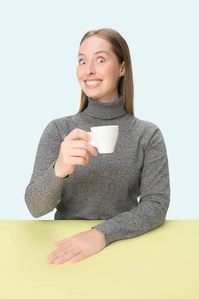 Bela mulher solitária sentada no estúdio e olhando triste segurando a xícara de café na mão. Closeup tonificado retrato — Fotografia de Stock