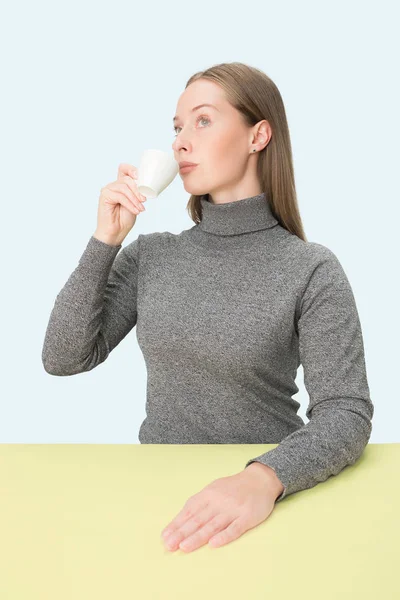 Belle femme seule assise au studio et regardant triste tenant la tasse de café dans la main. Portrait en gros plan — Photo