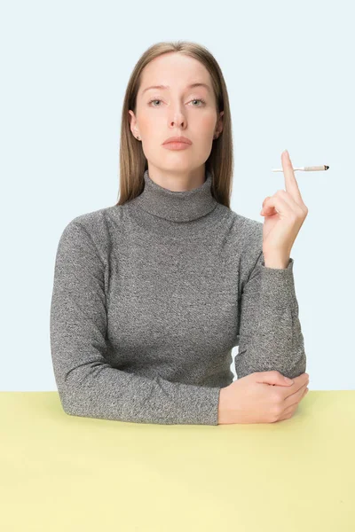 Gutaussehende junge Frauen rauchen, während sie am Tisch im Studio sitzen. Trendfarben — Stockfoto