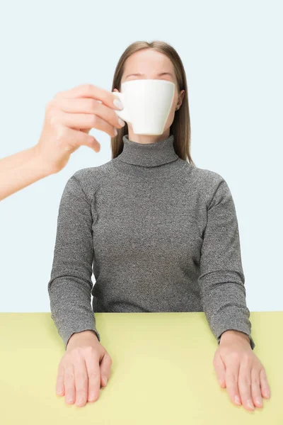 Das Konzept der Kaffeepause. Frau vor Kaffeetrinken im Studio am Tisch sitzend — Stockfoto