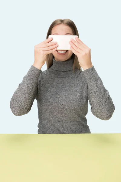 La mujer de negocios feliz sentado con el teléfono móvil sobre fondo rosa . — Foto de Stock