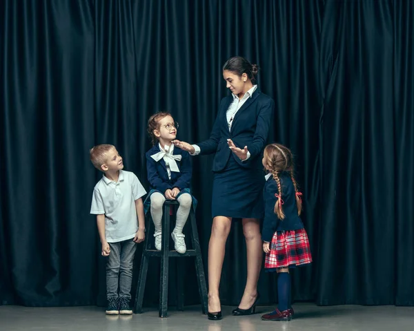 Roztomilý elegantní děti na pozadí tmavě studio. Krásné dospívající dívky a chlapci stáli — Stock fotografie