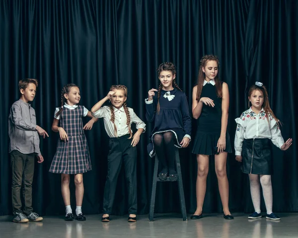 Niedliche stylische Kinder auf dunklem Studiohintergrund. die schönen jugendlichen Mädchen und Jungen, die zusammen stehen — Stockfoto