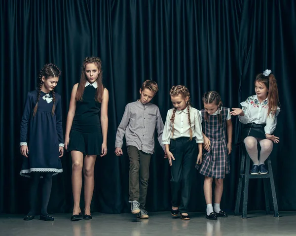 Симпатичные стильные дети на темном фоне студии. Красивые девочки-подростки и мальчик стоят вместе — стоковое фото