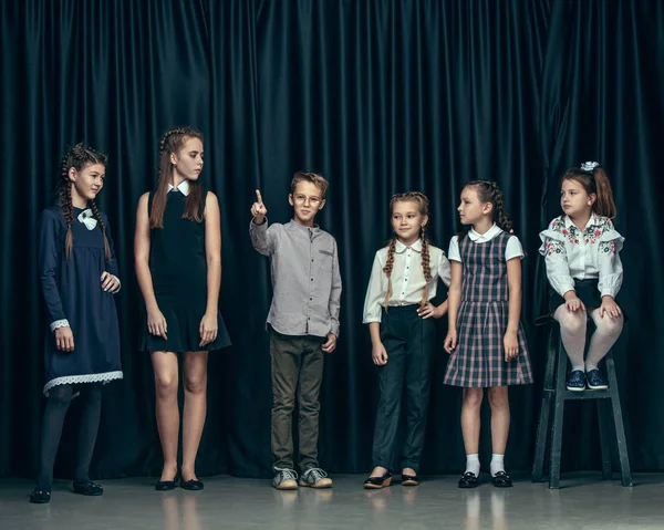 Lindos niños con estilo en el fondo del estudio oscuro. La hermosa adolescente niñas y el niño de pie juntos —  Fotos de Stock