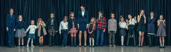 Cute stylish children on dark studio background. The beautiful teen girls and boy standing together