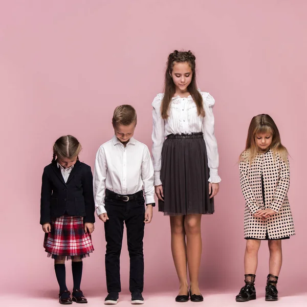 Милі стильні діти на рожевому студійному фоні. Красиві дівчата-підлітки і хлопчик стоять разом — стокове фото