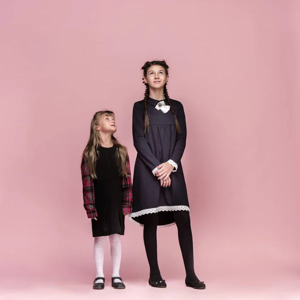 Lindos niños con estilo en el fondo del estudio rosa. La hermosa adolescente niñas de pie juntos — Foto de Stock