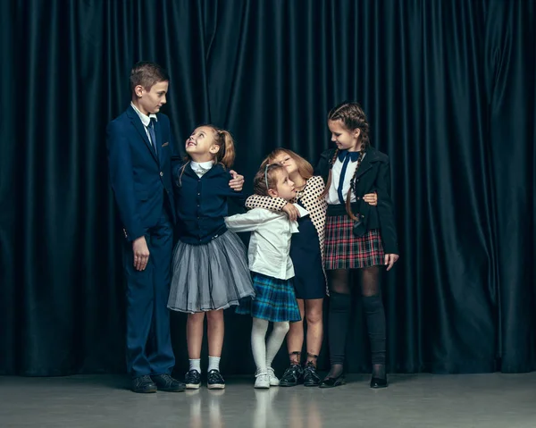 Niedliche stylische Kinder auf dunklem Studiohintergrund. die schönen jugendlichen Mädchen und Jungen, die zusammen stehen — Stockfoto