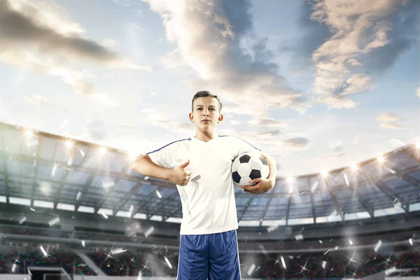 Giovane ragazzo con pallone da calcio che fa calcio volante allo stadio — Foto Stock