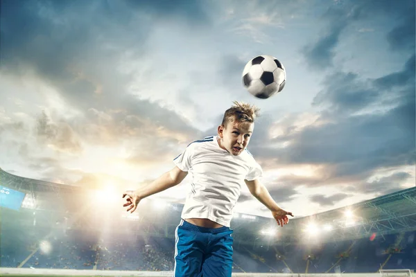 Young boy with soccer ball doing flying kick at stadium