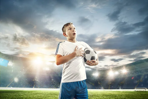 Young boy with soccer ball doing flying kick at stadium