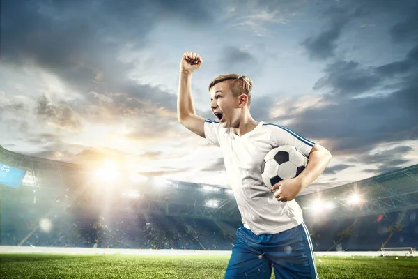 Niño con pelota de fútbol haciendo patada voladora en el estadio — Foto de Stock