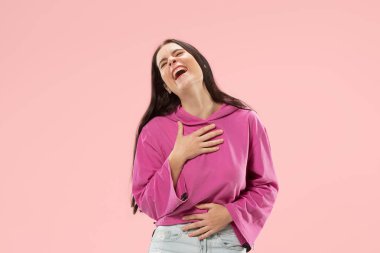 Ayakta ve pembe bir arka plan karşı gülümseyerek mutlu bir iş kadını.