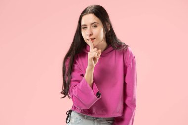 Pembe arka plan üzerinde elini arkasındaki sır fısıldayan genç kadın