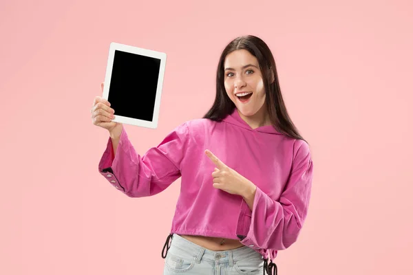 Портрет впевненої випадкової дівчини, що показує порожній екран ноутбука ізольований на рожевому фоні — стокове фото
