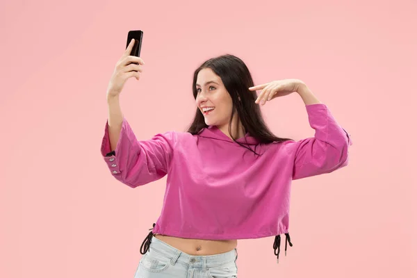 Retrato de uma menina casual sorridente feliz mostrando telefone celular tela em branco isolado sobre fundo rosa — Fotografia de Stock