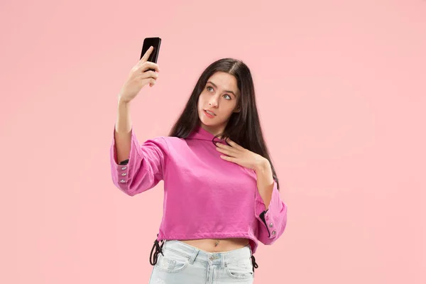 Portret van een gelukkig lachend casual meisje tonen leeg scherm mobiele telefoon geïsoleerd op roze achtergrond — Stockfoto