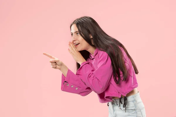Die junge Frau flüstert ein Geheimnis hinter ihrer Hand über rosa Hintergrund — Stockfoto