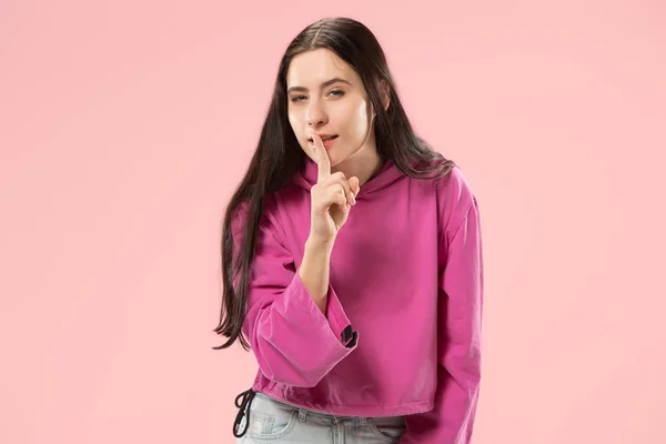 A fiatal nő suttogott a titok mögött a kezét, mint rózsaszín háttér — Stock Fotó