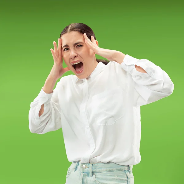 Den unga känslomässiga arg kvinna skrikande på gröna studio bakgrund — Stockfoto