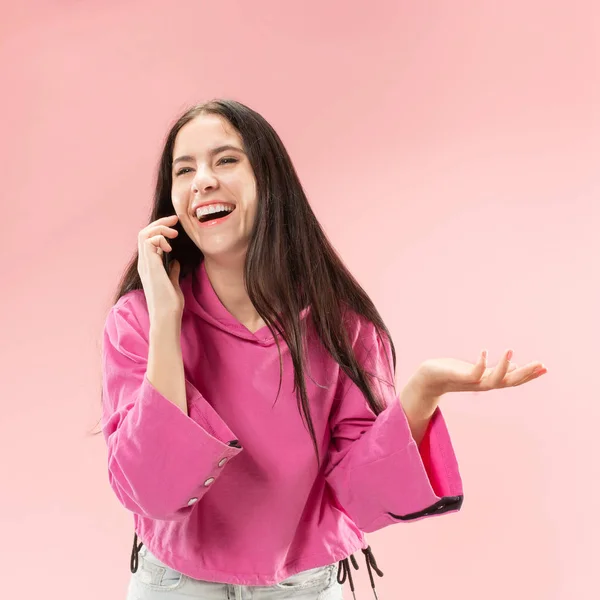 Junge schöne Frau mit Handy-Studio auf rosa Hintergrund — Stockfoto